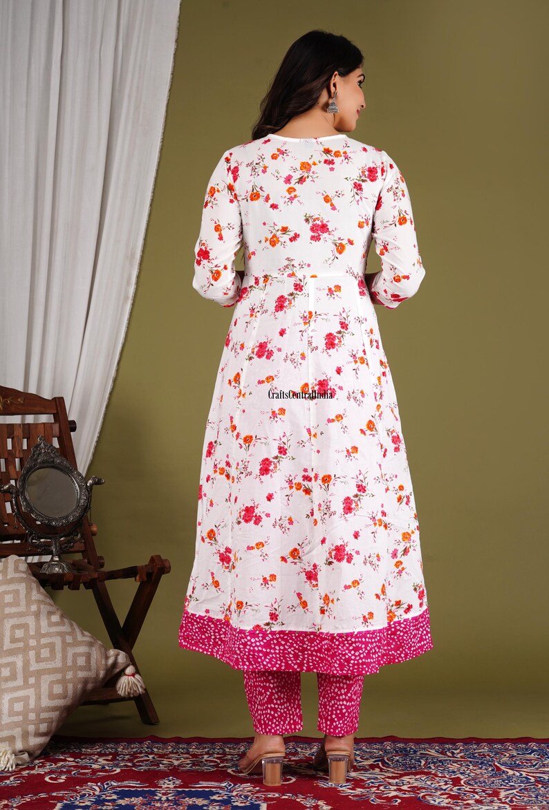 May include: A white floral print dress with a pink trim and matching pink pants. The dress has a V-neck and 3/4 sleeves.