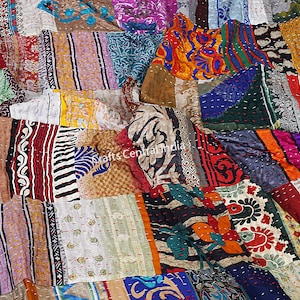 Könnte beinhalten: Eine farbenfrohe Patchwork-Decke aus recycelten Seiden-Saris. Die Decke besteht aus vielen verschiedenen Farben und Mustern, darunter florale, geometrische und Paisley-Designs. Die Decke ist handgenäht und hat einen einzigartigen Vintage-Look.