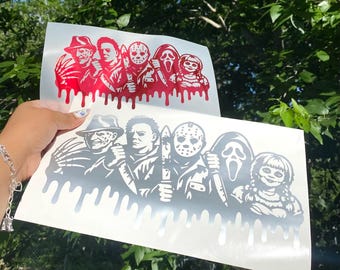 May include: Two rectangular adhesive decals featuring a graphic illustration of five horror movie characters arranged in a row. The designs include a clawed figure, a masked slasher, a hockey-masked killer, a ghost-faced figure, and a doll, with a dripping paint effect at the bottom. One decal is red and the other is black.
