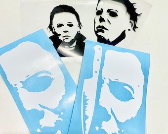 Puede incluir: Calcomanías de vinilo blanco y negro con la imagen de un personaje de película de terror. Las calcomanías incluyen una cara y una cara con un cuchillo sobre un fondo azul claro. La imagen también muestra otras dos calcomanías de caras.