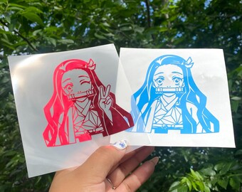 May include: Two square vinyl decals featuring a stylized anime character with long hair and a bamboo muzzle. One decal is printed in a vibrant hot pink, while the other is in a bright cyan blue. Both designs show the character making a peace sign.