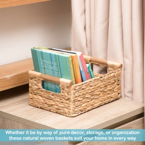 May include: A natural woven seagrass basket with wooden handles, filled with books. The basket is sitting on a wooden surface.