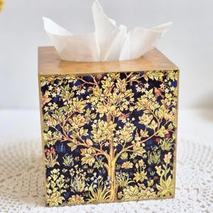 May include: A wooden tissue box cover with a floral design featuring a tree with yellow leaves and birds on a dark blue background.