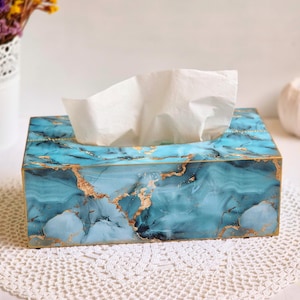 May include: A blue and gold marble tissue box cover. The cover has a decorative marble pattern with gold accents.