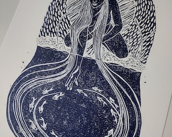 May include: A blue and white linocut print of a woman with long hair pouring her hair into a pool of water with fish swimming around. The woman is sitting on a rock and her hair is flowing down into the water.