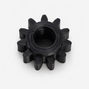May include: A black gear with ten teeth and a circular center hole. The object features a textured surface with visible horizontal layers, indicating a 3D printed construction. The gear is circular with a uniform black finish throughout.