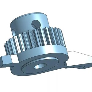 May include: A silver-colored metal gear with a toothed edge and a small hole in the center. The gear is attached to a smaller, flat piece of metal with a rounded edge.
