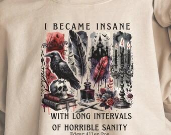 Puede incluir: Una sudadera beige con un estampado gráfico de un cuervo, velas y una cita de Edgar Allan Poe. La cita dice "Me volví loco con largos intervalos de horrible cordura".