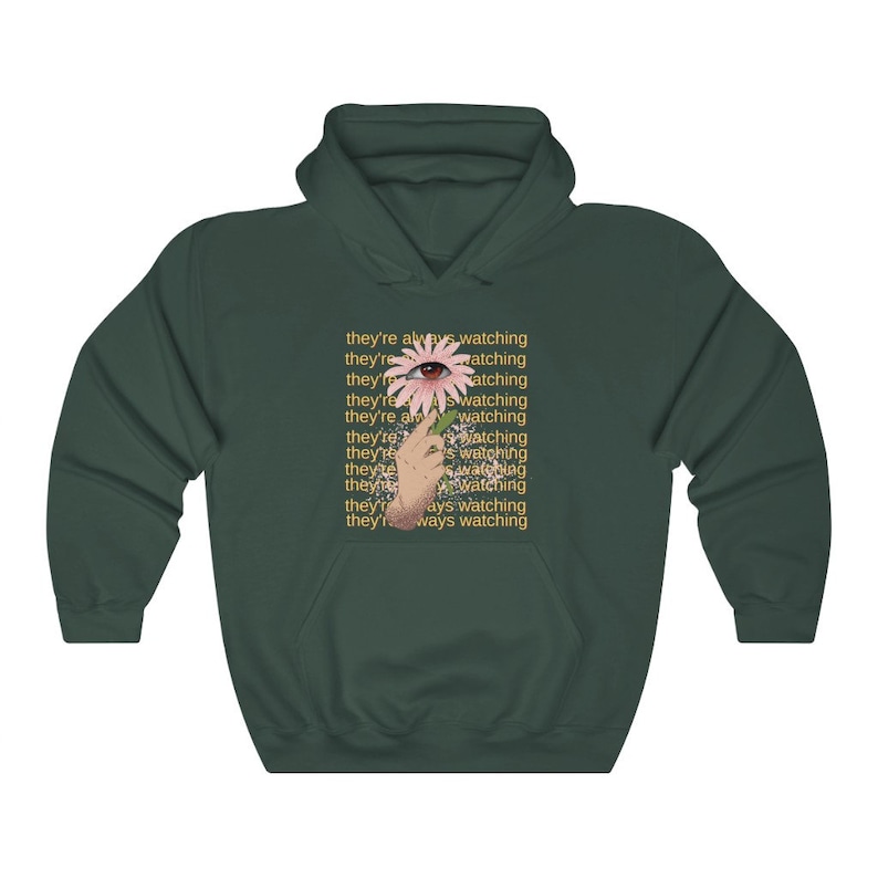 May include: A dark green hoodie with a pink flower and an eye in the center. The text "they're always watching" is repeated multiple times in yellow.