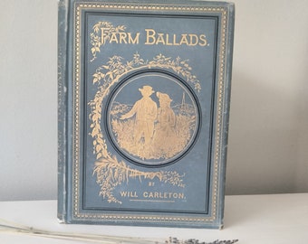 Puede incluir: Un libro azul vintage con letras doradas titulado "Farm Ballads" de Will Carleton. La portada presenta una ilustración dorada de una pareja de pie en un campo.