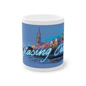 Könnte beinhalten: Weiße Keramiktasse mit blauem Hintergrund, die eine Stadtlandschaft mit einem hohen Kirchturm und dem Text "Giasng Church" in einem blauen Neon-Stil zeigt.