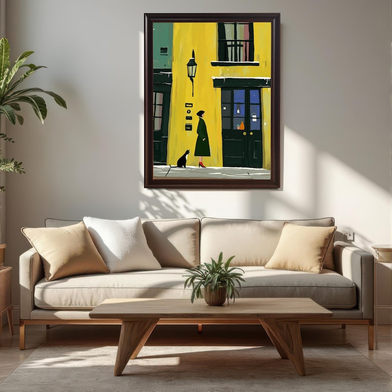 A framed wall art print in a dark coffee-colored frame is leaning against a white wall above a beige couch in a living room setting.