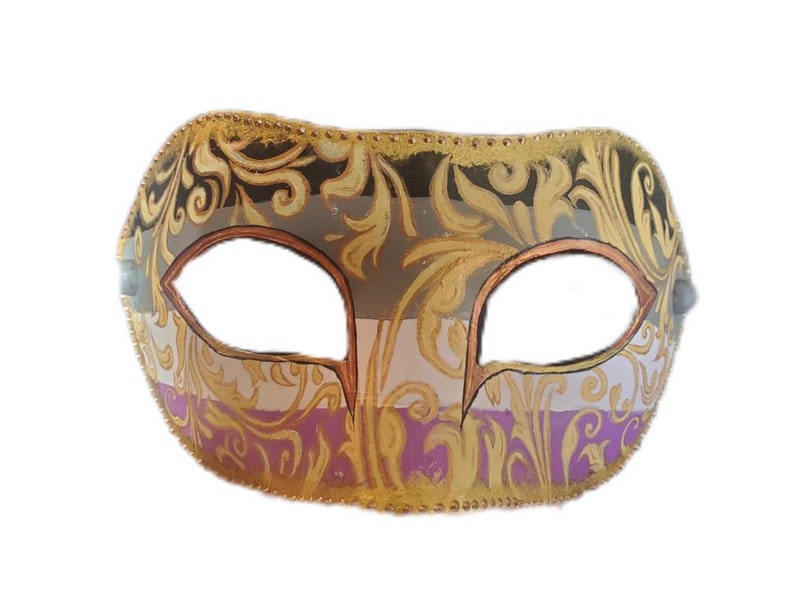 K&ouml;nnte beinhalten: Eine dekorative Maske mit einem verzierten Design. Die Maske hat ein Gold-, Schwarz-, Grau- und Lila-Farbschema. Die Augen&ouml;ffnungen sind braun umrandet. Die Maske ist mit goldener Filigranarbeit und einem goldenen Besatz verziert.