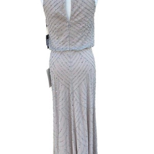 May include: A silver sequined halter dress with a geometric pattern. The dress has a keyhole back and a fitted bodice. The skirt is a-line and falls to the floor.