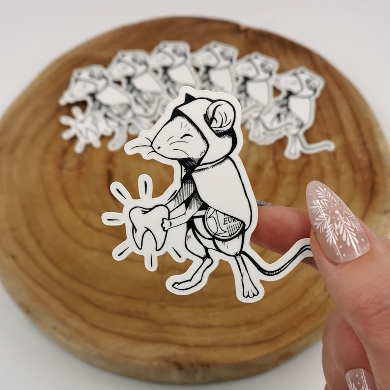 Sticker représentant la petite souris, style tatouage, présenté à la main sur un fond en bois