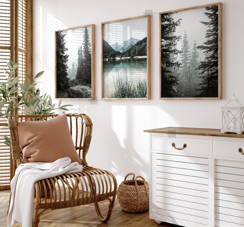 Puede incluir: Tres impresiones art&iacute;sticas enmarcadas con paisajes de bosques y lagos serenos en tonos apagados. Las impresiones se exhiben sobre una silla de mimbre con un coj&iacute;n terracota y una manta blanca. Una cesta tejida y un mueble blanco completan la decoraci&oacute;n.