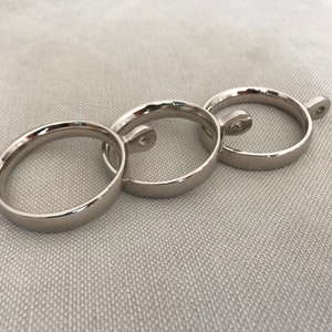 May include: Three silver metal curtain rings with a small hook on the side of each ring.