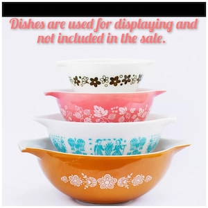 Puede incluir: Una pila de cuatro cuencos mezcladores Pyrex vintage. Los cuencos son blancos, rosas, turquesas y naranjas, cada uno con un diseño floral o estampado diferente. El cuenco superior es blanco con flores marrones. El texto en la parte superior dice "Los platos se utilizan para exhibir y no están incluidos en la venta."