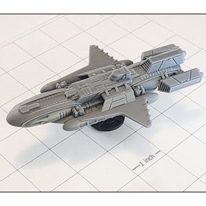 May include: A gray spaceship model with detailed features, including wings, multiple compartments, and a sleek design. The model is approximately 1 inch in length, resting on a black base, and set against a grid background.