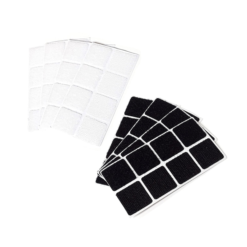 May include: A set of black and white adhesive squares. The squares are arranged in a grid pattern and are designed to be used for attaching items to surfaces.