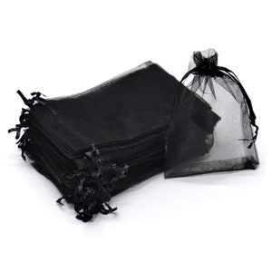 May include: A stack of black sheer organza gift bags with a single bag laying flat. The bags have a drawstring closure.