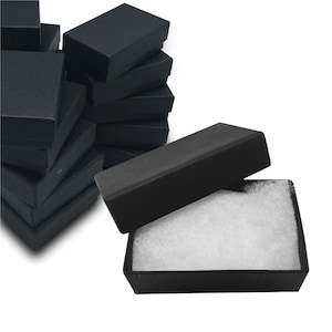 May include: A stack of black cardboard boxes with a single box open, revealing white foam padding inside. The boxes are ideal for packaging small items.
