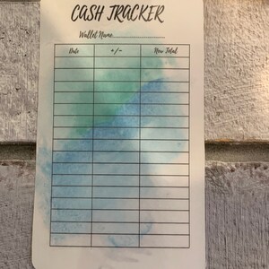 May include: A white cash tracker card with the words "CASH TRACKER" in black script. The card has a watercolor design in shades of blue and green. It includes sections for date, +/- and new total.