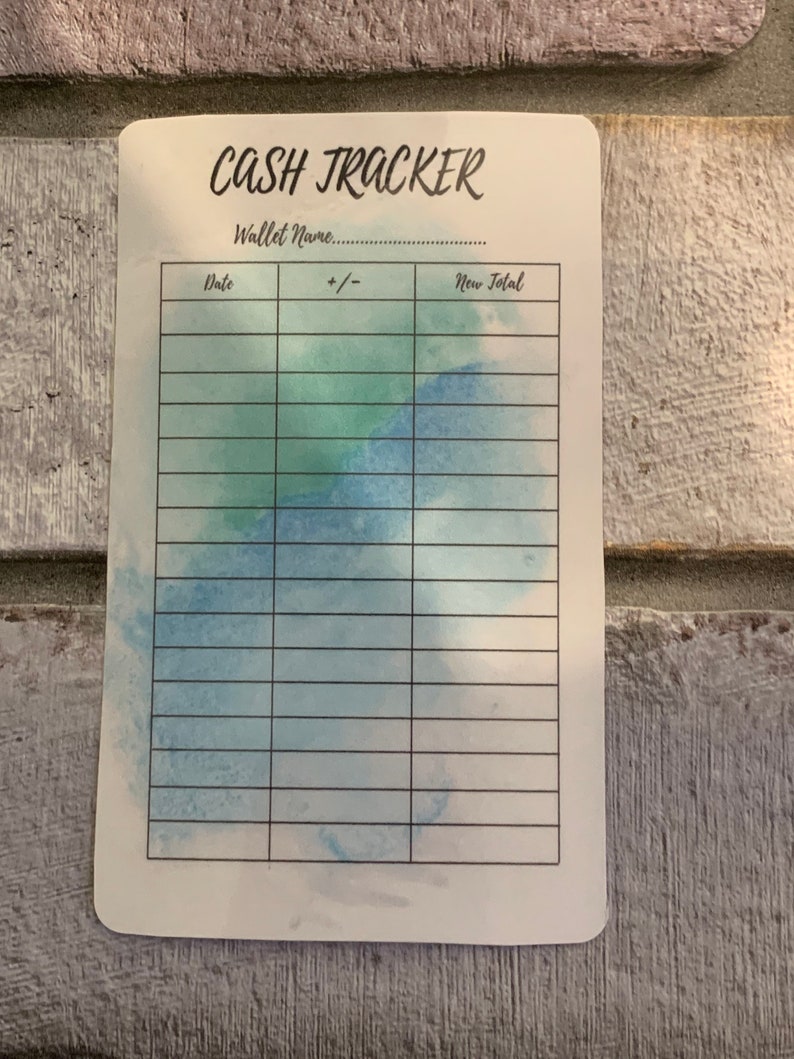 May include: A white cash tracker card with the words "CASH TRACKER" in black script. The card has a watercolor design in shades of blue and green. It includes sections for date, +/- and new total.