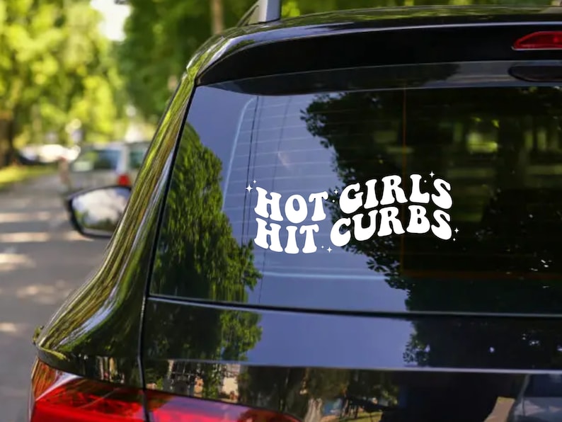 May include: A black car with a white vinyl sticker on the back window that reads "Hot Girls Hit Curbs".