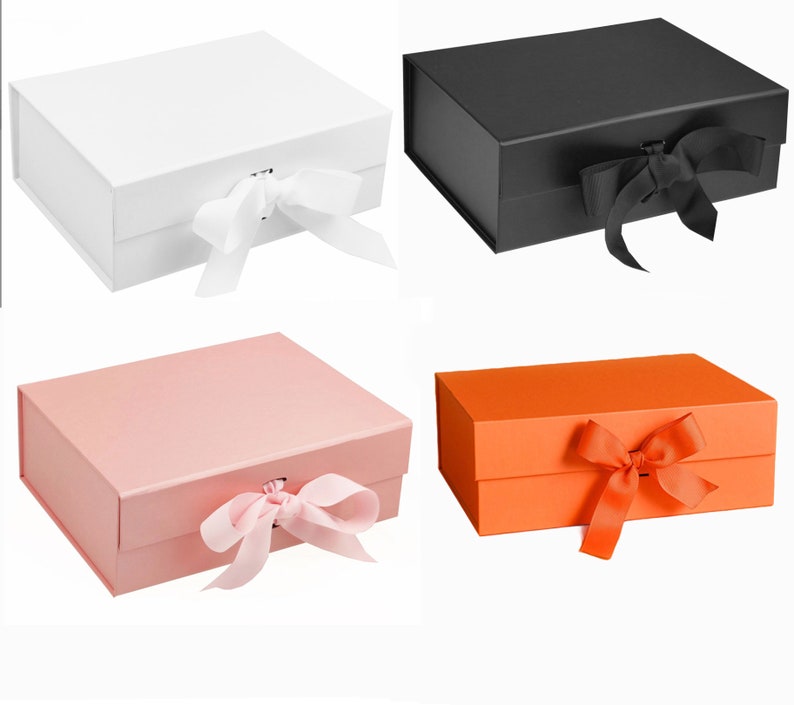 Puede incluir: Cuatro cajas de regalo con tapas, cada una atada con una cinta. Las cajas son blancas, negras, rosas y naranjas.