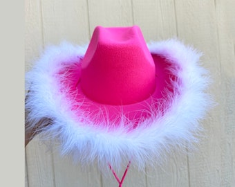 May include: A pink cowboy hat with a white feather trim and a pink string tie.