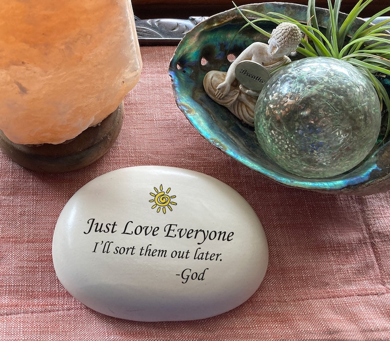 May include: White stone with a yellow sun and the text "Just Love Everyone I'll sort them out later. -God"