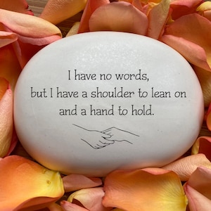 May include: White painted rock with the text "I have no words, but I have a shoulder to lean on and a hand to hold."  The rock is surrounded by orange rose petals.