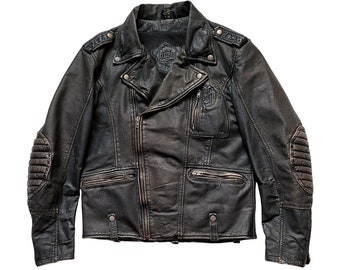 Könnte beinhalten: Eine schwarze Lederjacke im Motorrad-Stil mit Reißverschluss, mehreren Taschen und einem Used-Look. Die Jacke hat ein Logo auf der linken Brust und einen Patch auf dem Rücken.