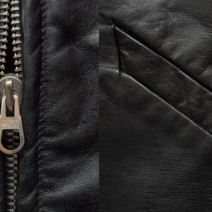 May include: Close-up of a black leather jacket with a silver zipper. The zipper has the word "W.I.D.O." on the pull tab.