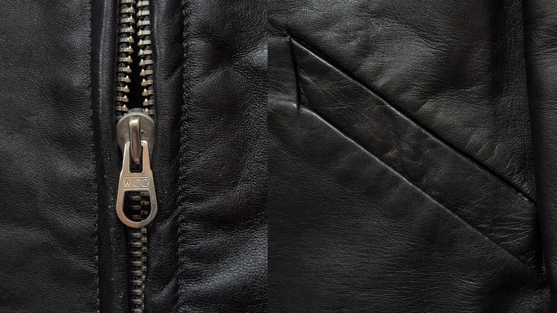 May include: Close-up of a black leather jacket with a silver zipper. The zipper has the word "W.I.D.O." on the pull tab.