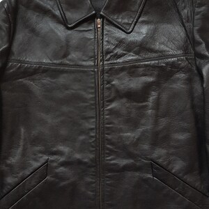May include: A black leather jacket with a zipper closure and a collar. The jacket has two pockets on the bottom and a label that reads "Made in Mongolia".