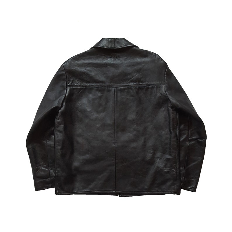 May include: A black leather jacket with a collared neckline and a button closure. The jacket has long sleeves and a relaxed fit.