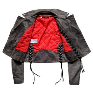 May include: A gray suede leather jacket with black lace-up detailing on the sides and a red quilted lining.