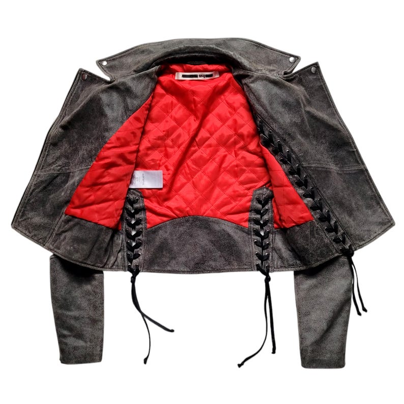 May include: A gray suede leather jacket with black lace-up detailing on the sides and a red quilted lining.