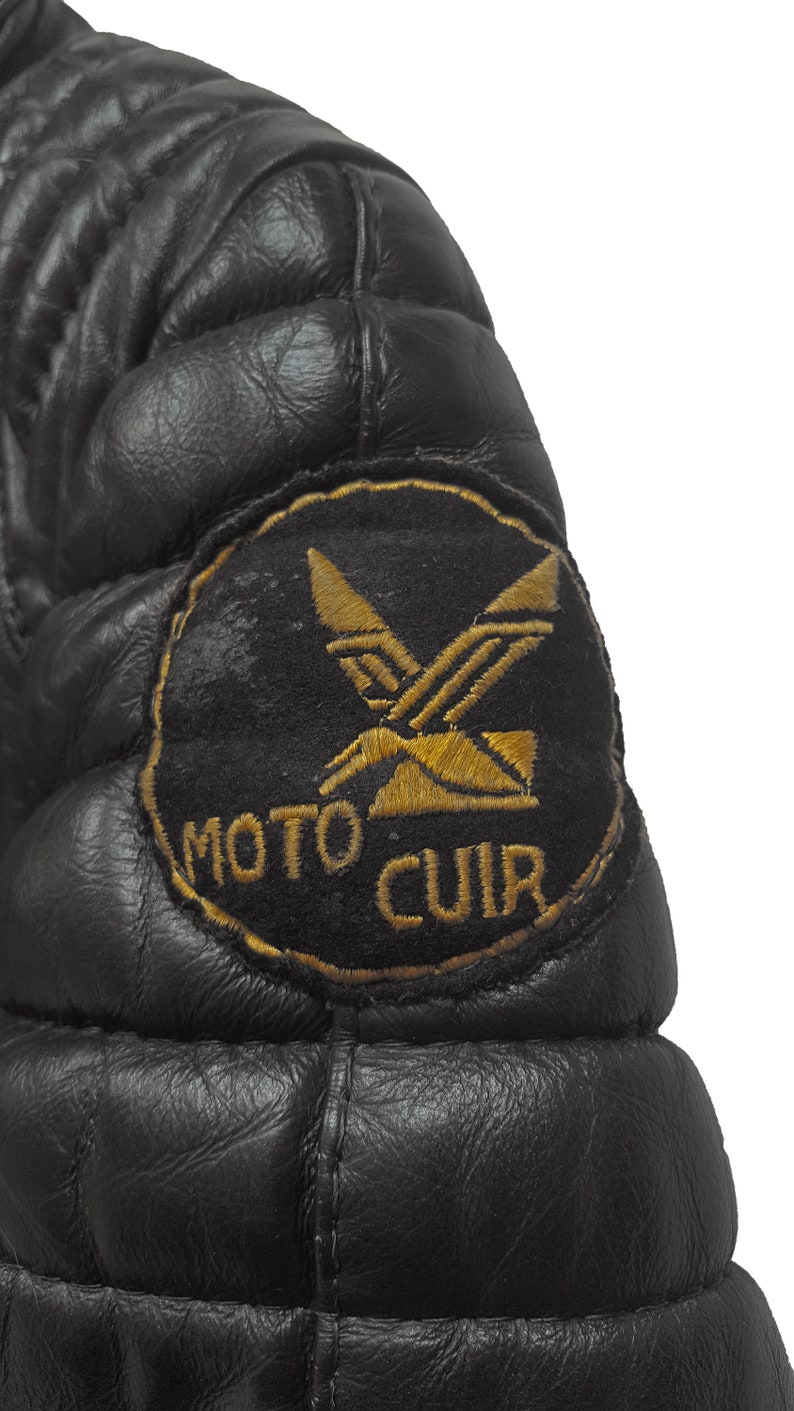 May include: Black leather jacket with a quilted design and a gold embroidered patch that says "MOTO CUIR" with a stylized X design.
