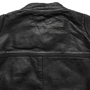 Może przedstawiać: Czarna sk&oacute;rzana kurtka ze st&oacute;jką i zamkiem błyskawicznym. Kurtka ma pikowane wzory na ramionach i plecach.