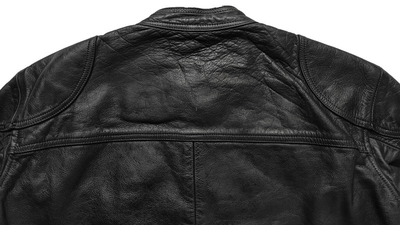 Może przedstawiać: Czarna sk&oacute;rzana kurtka ze st&oacute;jką i zamkiem błyskawicznym. Kurtka ma pikowane wzory na ramionach i plecach.