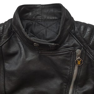 May include: Black leather motorcycle jacket with quilted shoulders and a zipper closure. The jacket has a gold zipper pull with a logo and a gold patch on the right sleeve with the text "MOTORCYCLE".