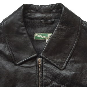 May include: Black leather jacket with a zipper closure and a collar. The jacket has a label that reads "Made in Mongolia".