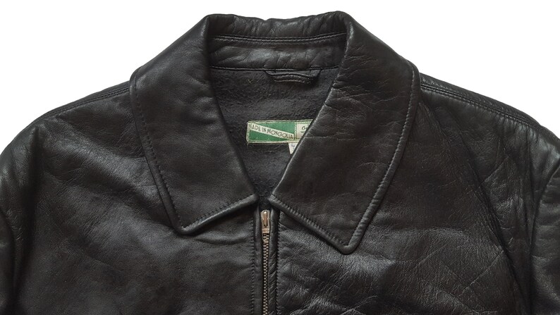 May include: Black leather jacket with a zipper closure and a collar. The jacket has a label that reads "Made in Mongolia".