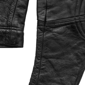 Może przedstawiać: Czarna sk&oacute;rzana kurtka o fakturowanej powierzchni. Kurtka zapinana na zamek błyskawiczny, z wykładanym kołnierzem.