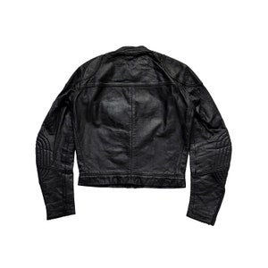 Może przedstawiać: Czarna sk&oacute;rzana kurtka motocyklowa z zamkiem błyskawicznym i pikowanymi detalami na rękawach.