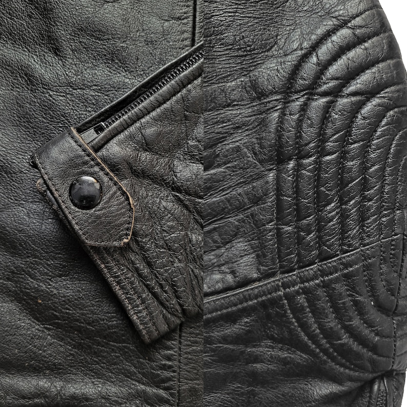 Może przedstawiać: Zbliżenie na czarną sk&oacute;rzaną kurtkę z zamkiem błyskawicznym i pikowanym wzorem na rękawie.