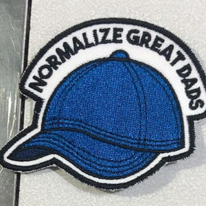 May include: A blue and white embroidered patch with the text "Normalize Great Dads" in a white circle around a blue baseball cap.